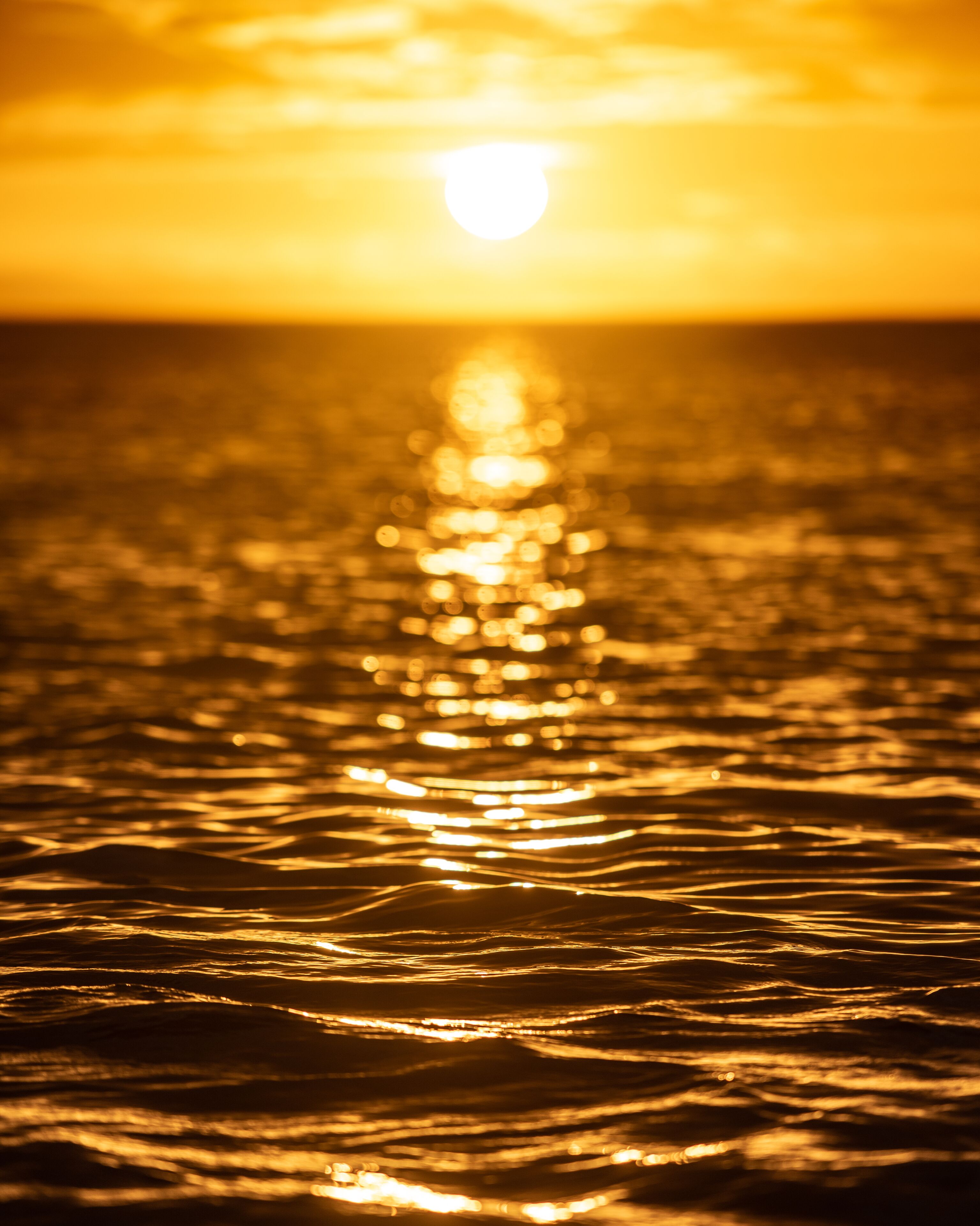 A sunset over a body of water with sunlight reflecting on the surface.