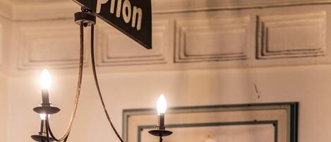 A reception sign with a chandelier and a framed abstract painting.