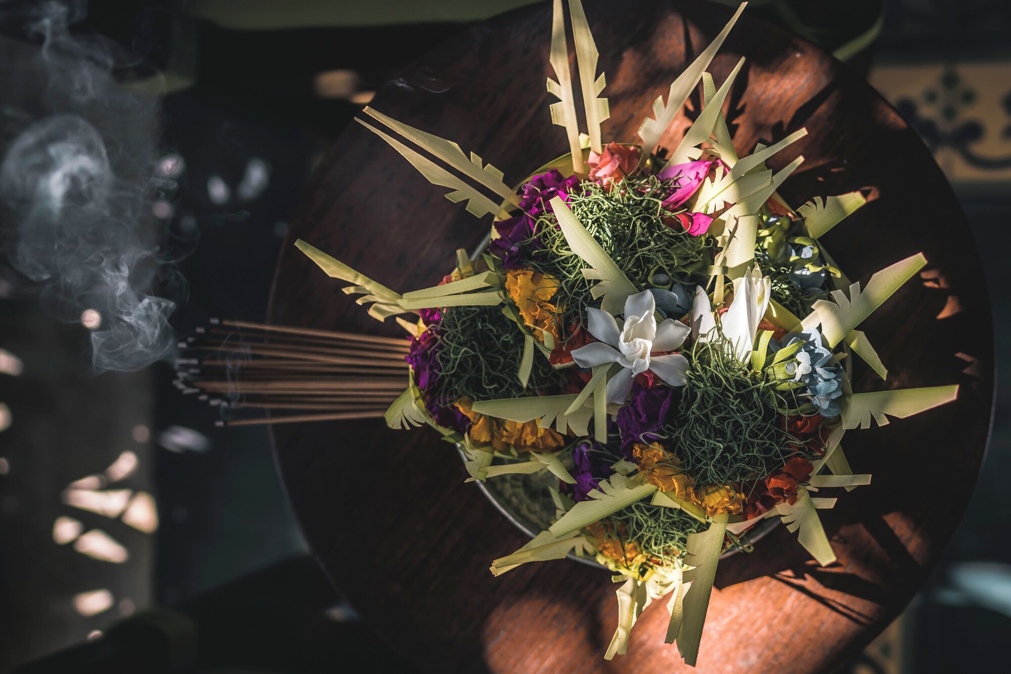 Eine Nahaufnahme einer Hand, die einen Blumenstrauß mit grünen Blättern und verschiedenen Blüten hält, möglicherweise für eine festliche Gelegenheit.