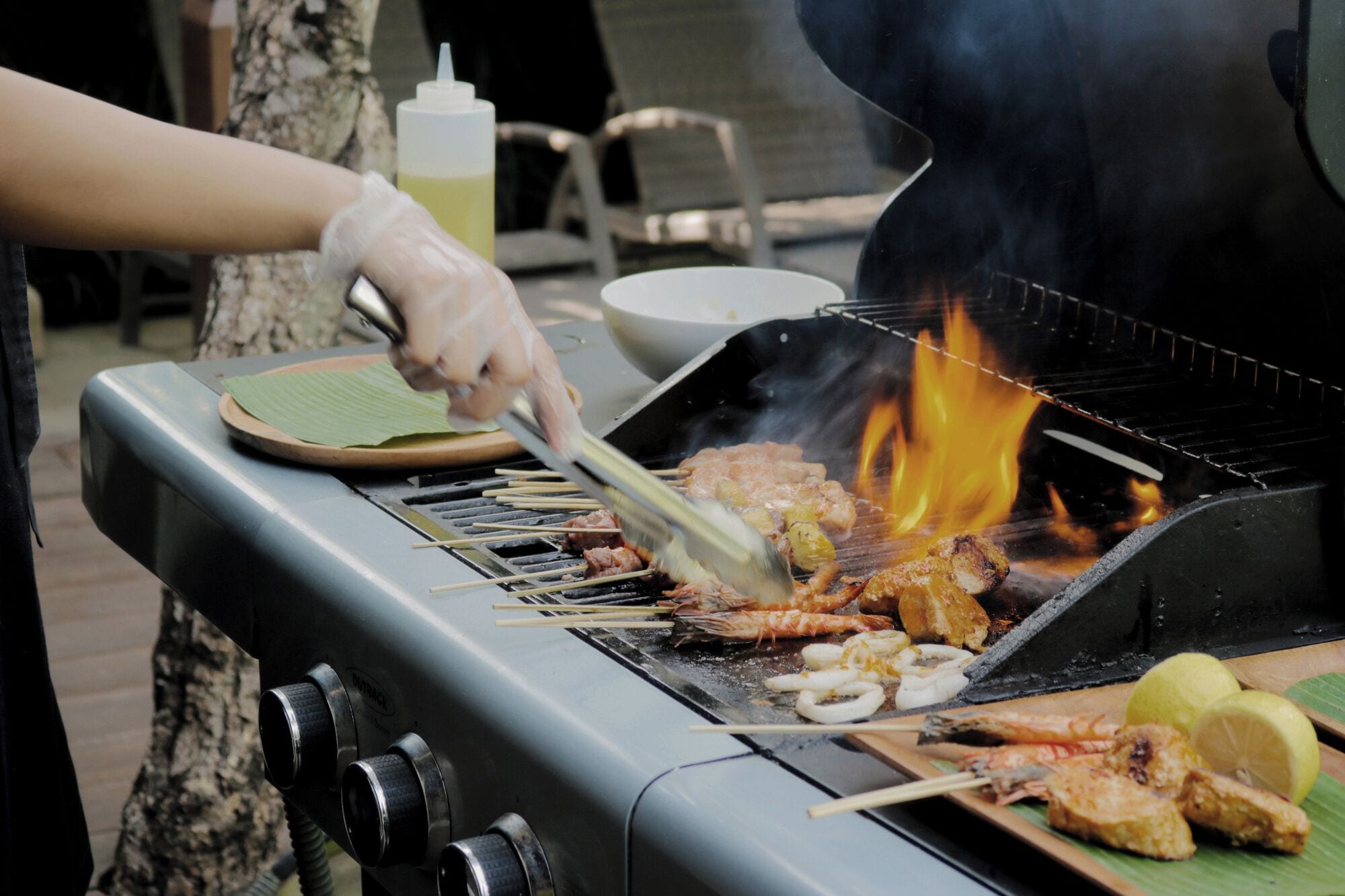 Eine Person grillt Essen auf einem Grill, darunter brennt ein Feuer.
