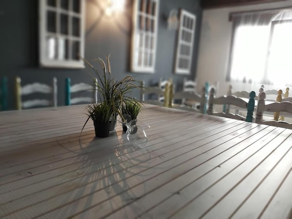 Una mesa de madera con plantas en macetas y una vista despejada a una ventana con barandal blanco.