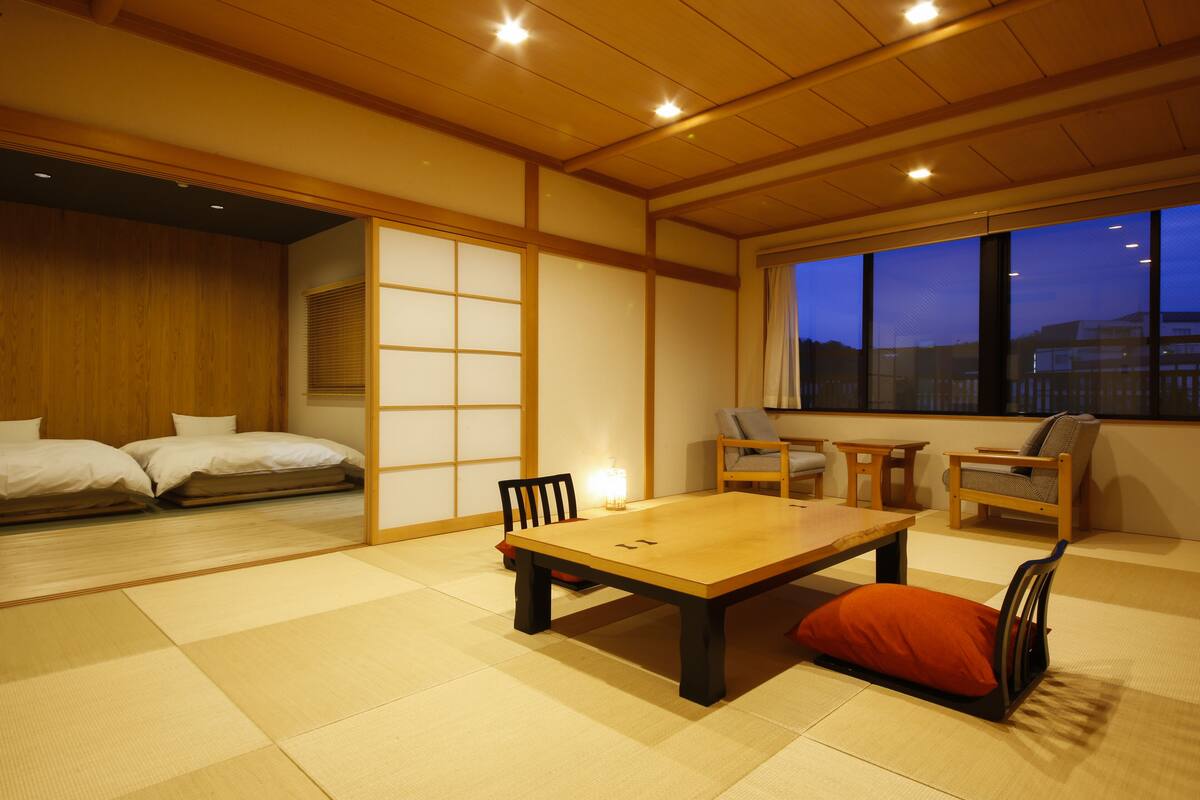 A traditional Japanese-style room with tatami flooring, a low table, and a futon bed.