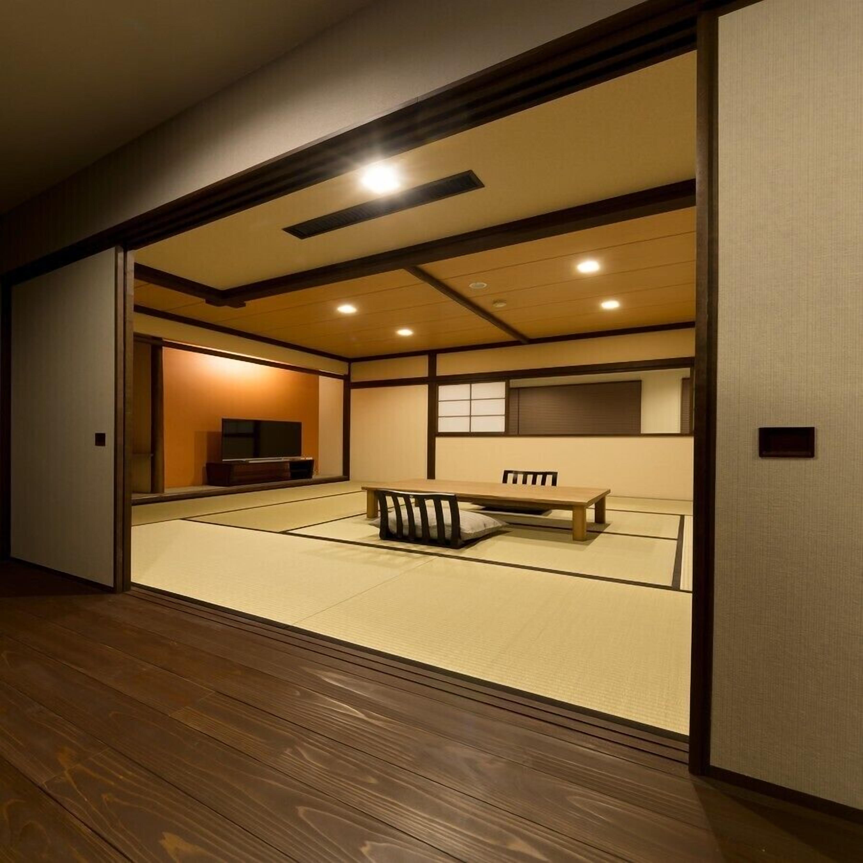 Um quarto japonês tradicional com tatames, uma mesa de madeira baixa e portas corrediças.