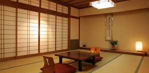A traditional Japanese room with tatami flooring, a low wooden table, and a sliding door with a grid pattern. - Hotel Kikyou (Kaga)
