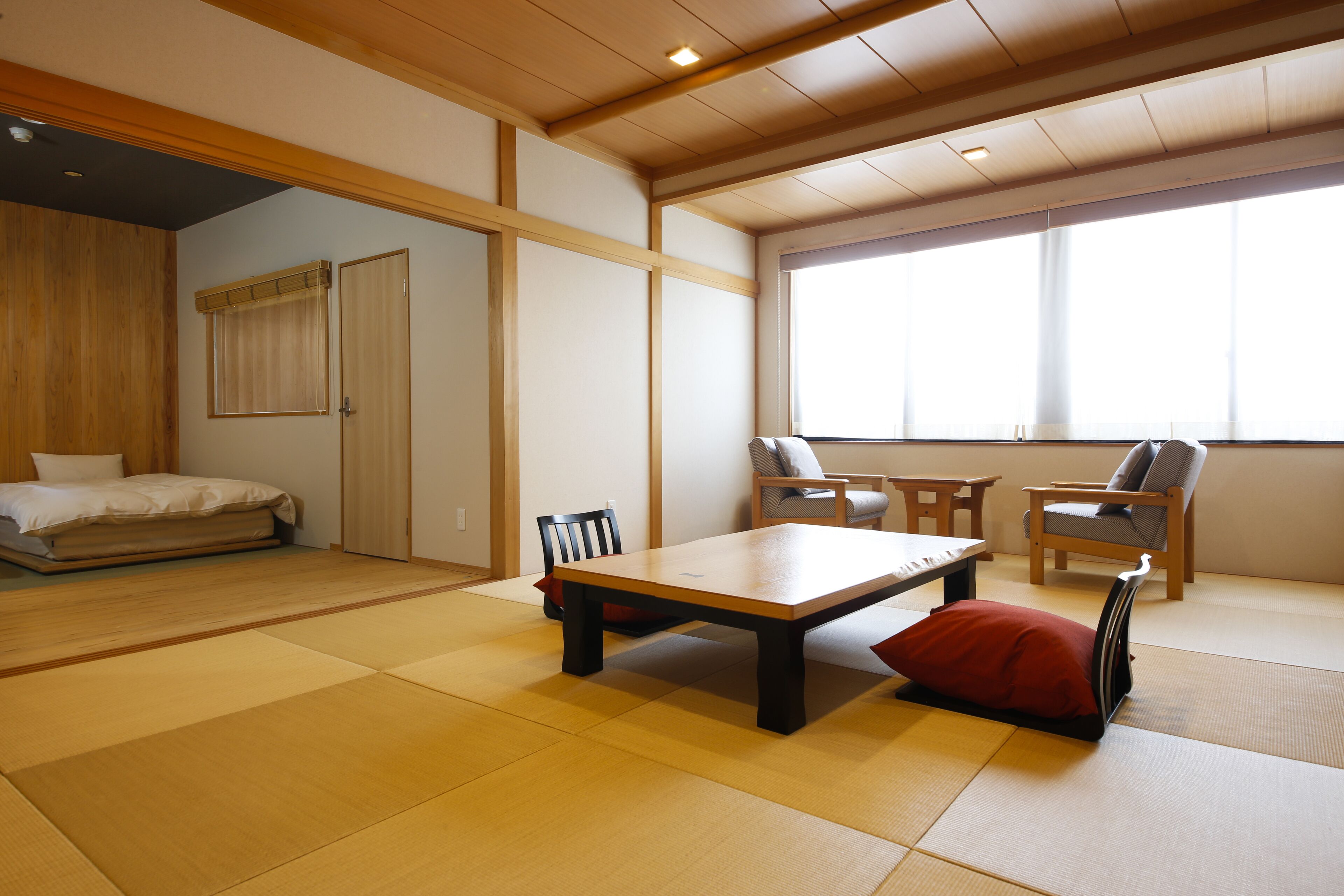 A traditional Japanese-style room with tatami flooring, a low wooden table, and two chairs.