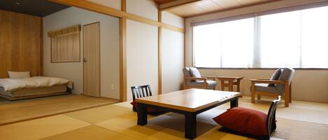 A traditional Japanese-style room with tatami flooring, a low wooden table, and two chairs.