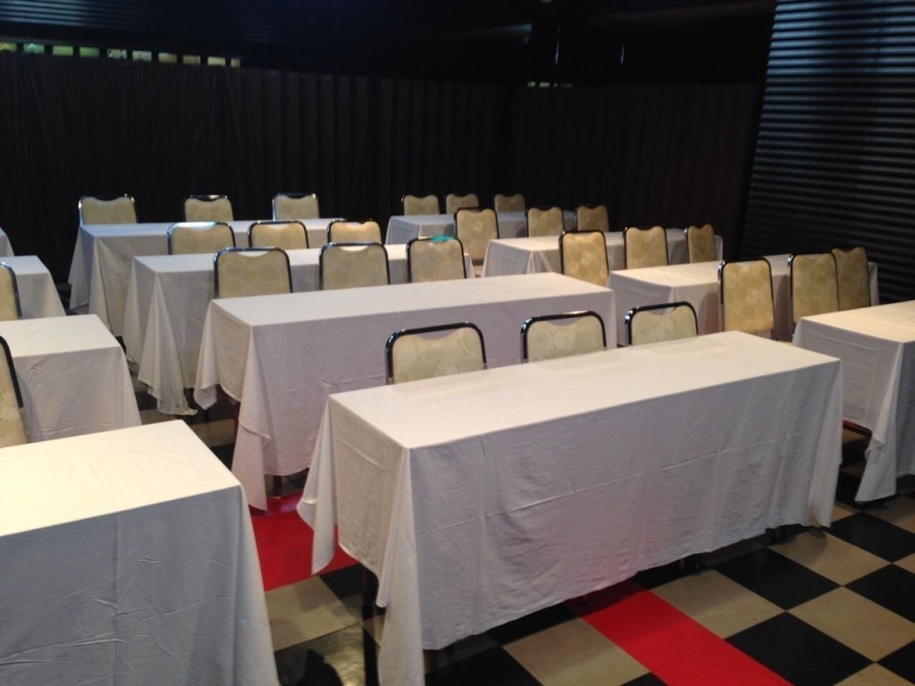 Un salón de conferencias con varias mesas y sillas dispuestas en filas.
