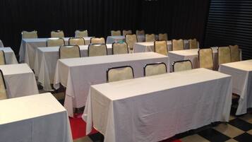 Un salón de conferencias con varias mesas y sillas dispuestas en filas.