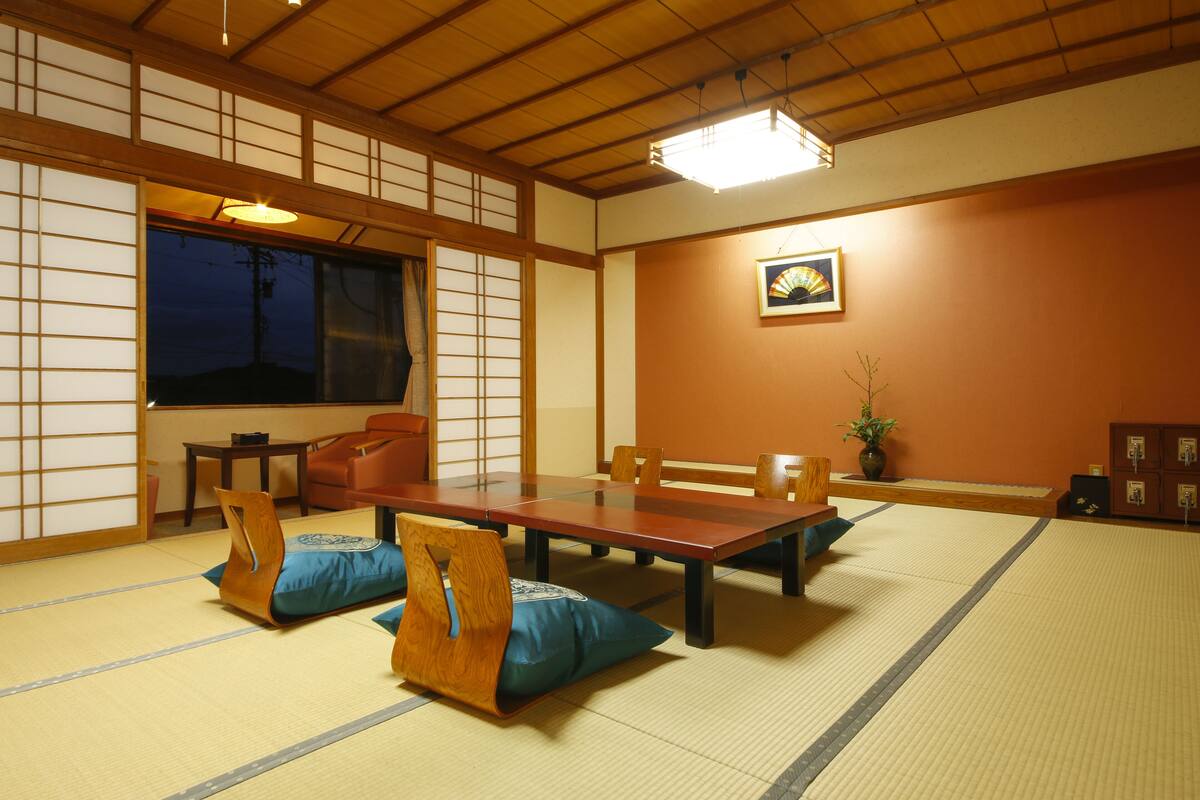 A traditional Japanese room with tatami flooring, a low table, and wooden chairs.