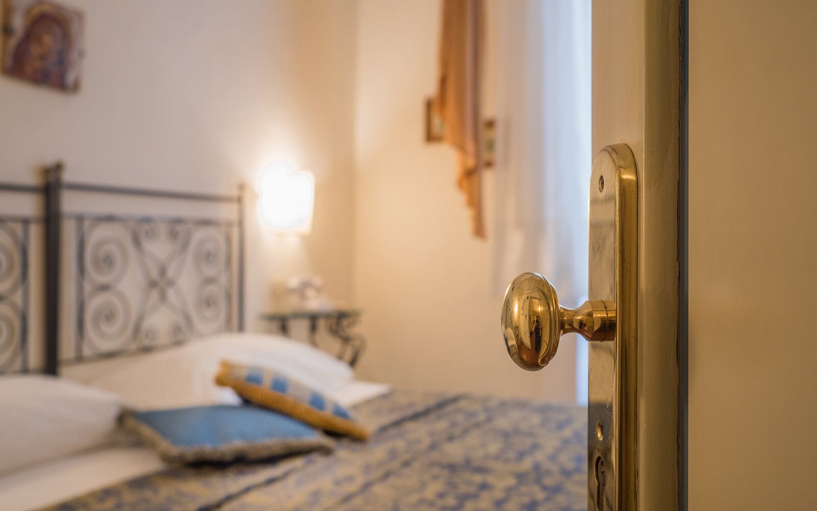 A room with a bed, a nightstand, a lamp, and a door with a brass handle.