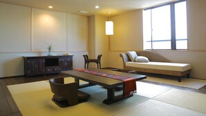A traditional Japanese-style room with tatami flooring, a low table, a sofa, and a cabinet. - Yamashiro Onsen Ryokan Tatami (Kaga)