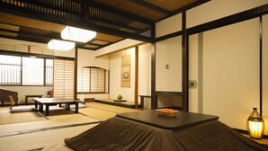 A traditional Japanese room with tatami flooring, a low table, cushions, and a lantern. - Yamashiro Onsen Ryokan Tatami (Kaga)