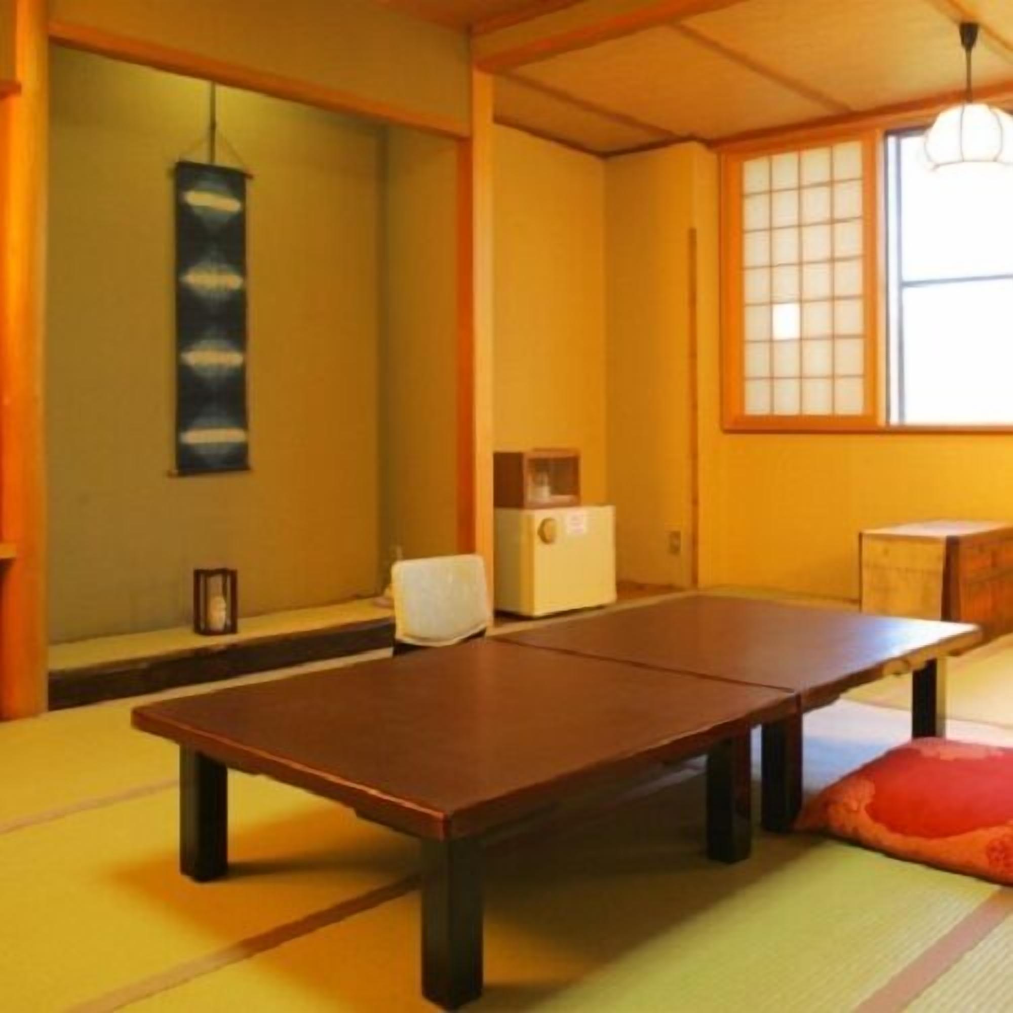 Een kamer met tatami matten, een lage tafel, een traditionele Japanse kachel en een raam met shoji schermen.