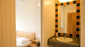 A hotel bathroom with a bed, a sink, and a mirror. - Hotel Klaus im Weinviertel (Wolkersdorf im Weinviertel)