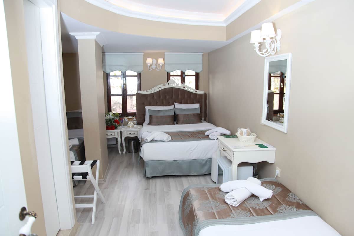 Una habitación de hotel con dos camas, un escritorio, una silla, un tocador y un espejo.