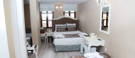 A hotel room with two beds, a desk, a chair, a vanity, and a mirror.