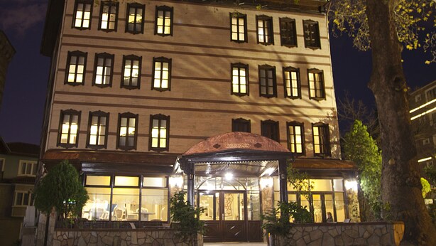 Un hotel de varios pisos con fachada de piedra, numerosas ventanas y una entrada central con marquesina.
