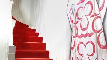 Escada com degraus revestidos em carpete vermelho e parede branca com cortina decorativa.