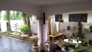 Un espace extérieur abrité, aménagé avec des sièges, des plantes en pot et offrant une vue sur la rue.