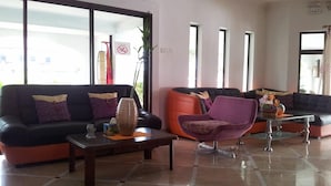 Un hall d’entrée moderne avec un canapé en cuir noir, un fauteuil violet et une table basse en verre.