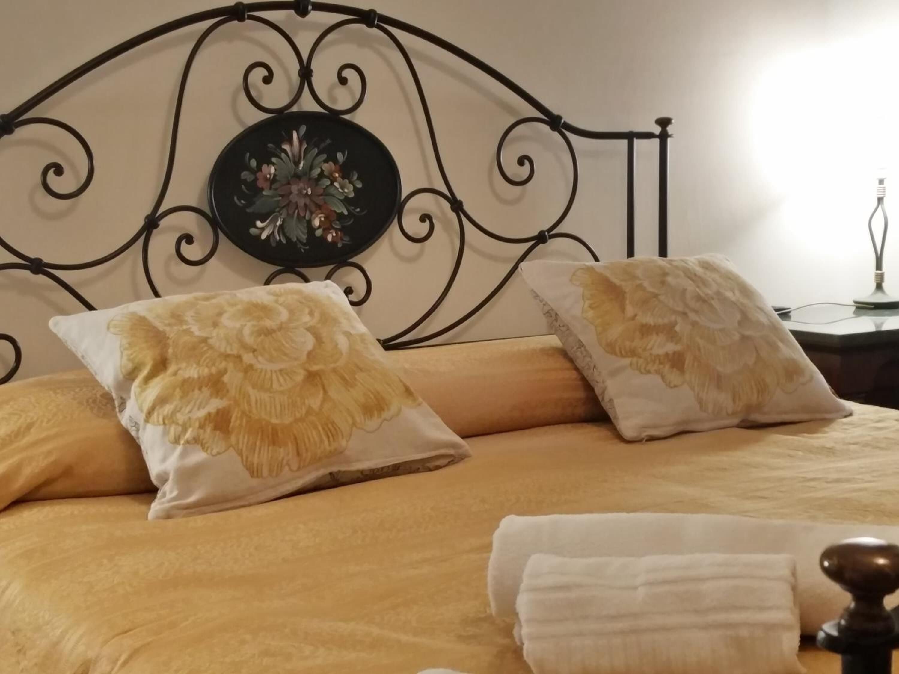 A bed with a decorative headboard, two pillows, and a bedside table with a lamp.