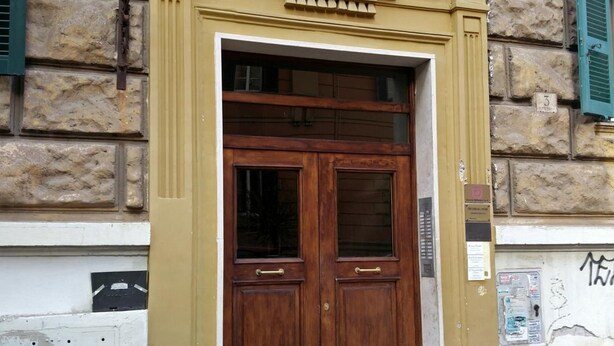 Ein Gebäude mit einer großen Holztür, einer Steinfront und einem kleinen Schild mit der Nummer 3.