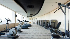A gym with treadmills, elliptical machines, and weight stations arranged in rows. - Impact Novo Condo Muang Thong Thani (Pak Kret)