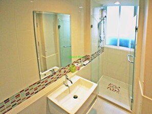 A modern bathroom with a large mirror, a white sink, and a glass shower enclosure. - Impact Novo Condo Muang Thong Thani (Pak Kret)