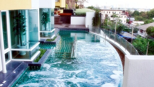 A modern hotel with a rooftop infinity pool, glass railings, and a view of the cityscape. - Impact Novo Condo Muang Thong Thani (Pak Kret)