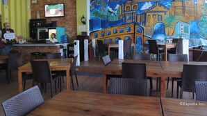 Een restaurant met houten tafels en stoelen, een televisiescherm en een muurschildering.