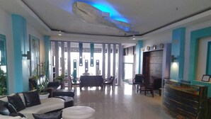 Een moderne lobby met een receptiebalie, zithoek en een groot raam.
