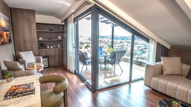 A modern living room with a large sliding glass door leading to a balcony with a city view. - Hotel Bosfora (Istanbul)