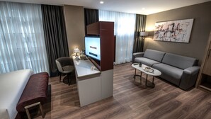 A modern hotel room with a sofa, a small desk with a computer, a coffee table, and a bench. - Hotel Bosfora (Istanbul)