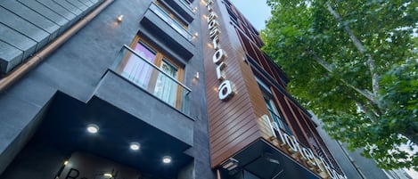 A hotel with a modern facade, featuring a prominent sign for 'Hotel Bostonia' and a visible entrance.