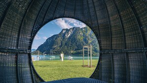 Une fenêtre circulaire offrant une vue sur un paysage montagneux et un lac.