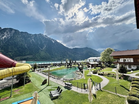 A mountain view with a pool, lounge chairs, and a red slide.. Kinderhotel Buchau
