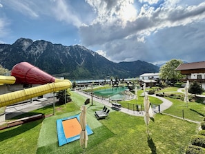 A pool area with a slide, a trampoline, and a view of mountains.