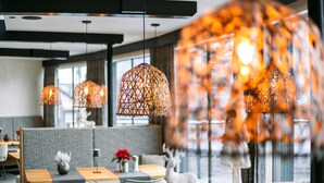 Un intérieur moderne agrémenté de luminaires suspendus aux motifs géométriques, d’un espace détente avec des bancs rembourrés et d’une statue de cerf décorative.