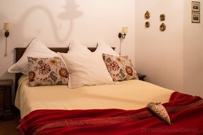 A bedroom with a bed, pillows, a red blanket, and wall-mounted lamps. - Il Casale Del Sogno (Ardea)