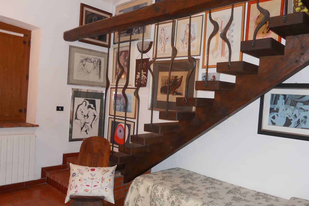 Eine Treppe mit Holzdielen und Metallgeländern, umgeben von verschiedenen gerahmten Kunstwerken an den Wänden.