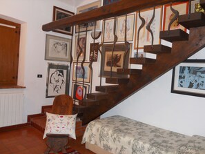 A staircase with wooden steps and metal railings, surrounded by various framed artworks on the walls. - Il Casale Del Sogno (Ardea)