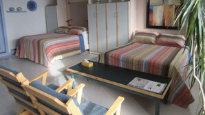 Una habitación con dos camas, una mesa, sillas, un armario y un espejo.