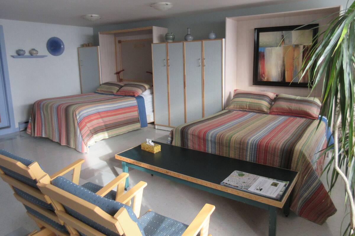 Ein Zimmer mit zwei Betten, einem Tisch, Stühlen, einem Kleiderschrank und einem Spiegel.