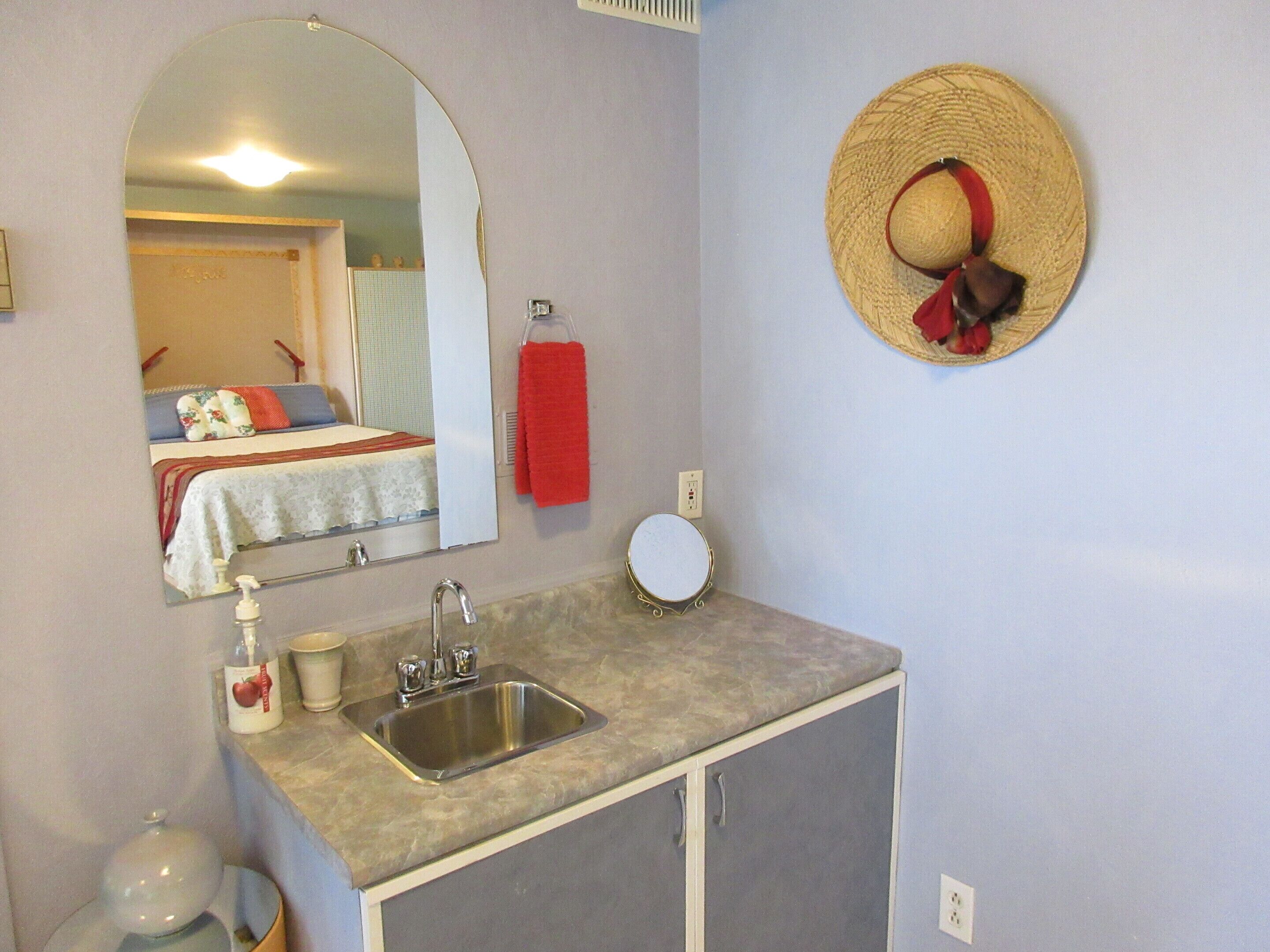 A bathroom with a sink, mirror, and towel rack.