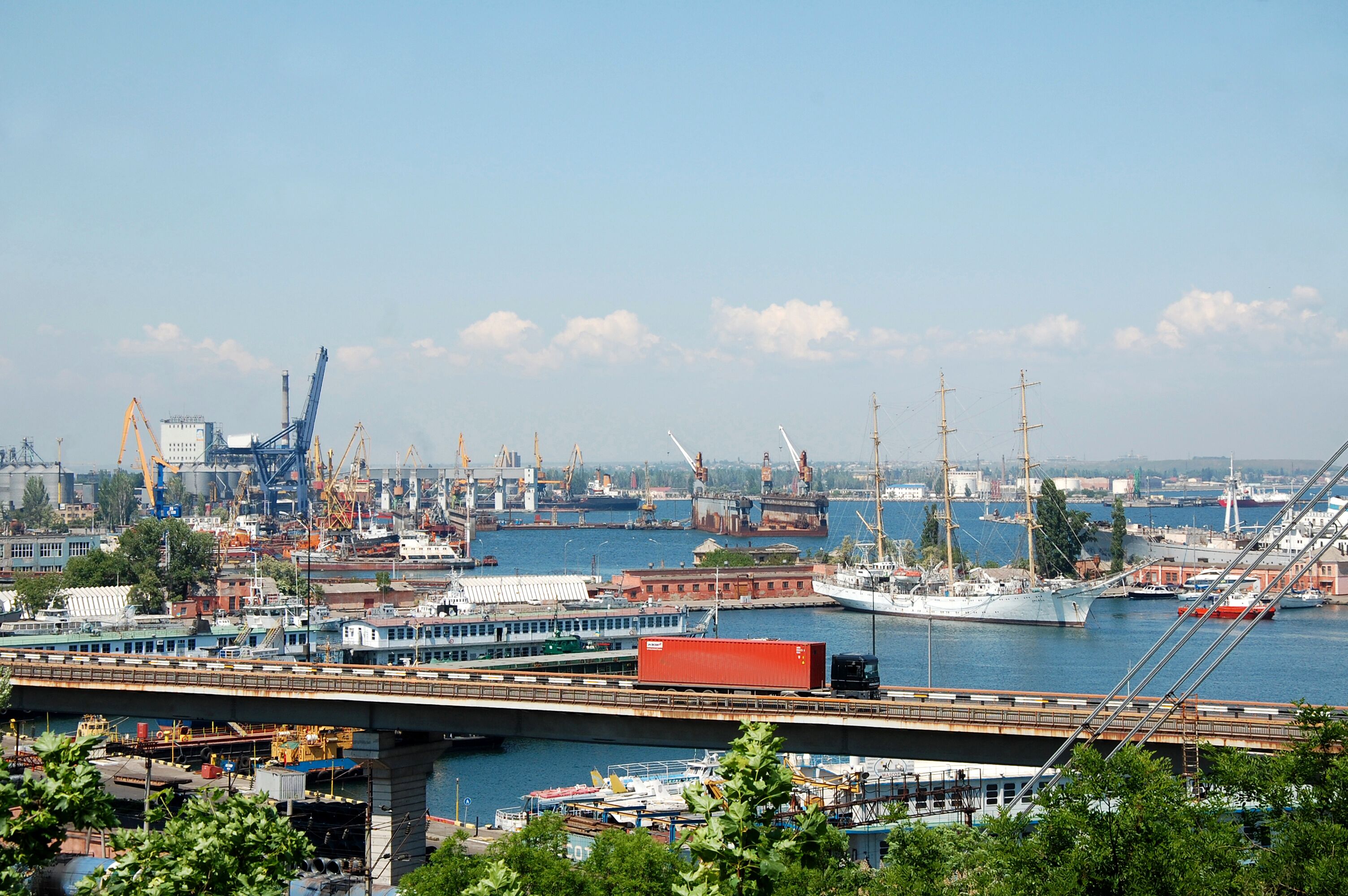 A harbor with cranes, ships, and a bridge.