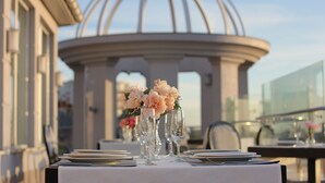A table set for a meal with a clear view of a glass balustrade and a building in the background.