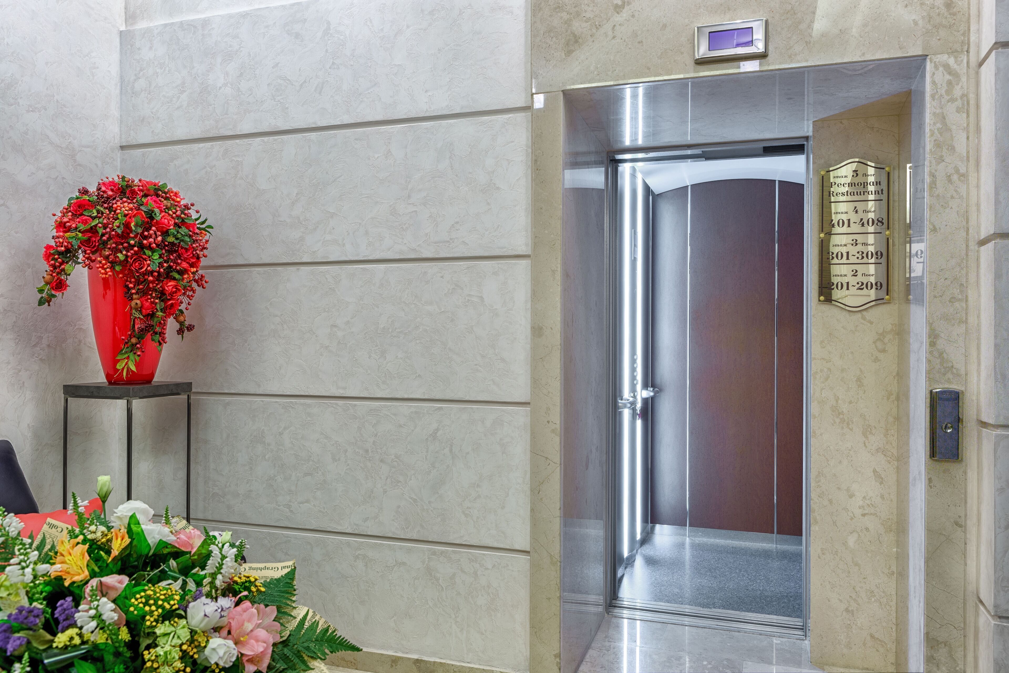 Un ascensor moderno con una pantalla digital y una placa que indica el piso del restaurante.