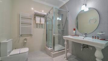 A modern bathroom with a glass-enclosed shower, a white pedestal sink, and a large mirror.