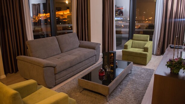 A modern living room with a grey sofa, a green armchair, and a coffee table. - Hotel Opera House (Skopje)
