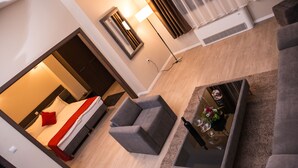 A modern living room with a sofa, a glass coffee table with a flower arrangement, a lamp, and an air conditioning unit. - Hotel Opera House (Skopje)